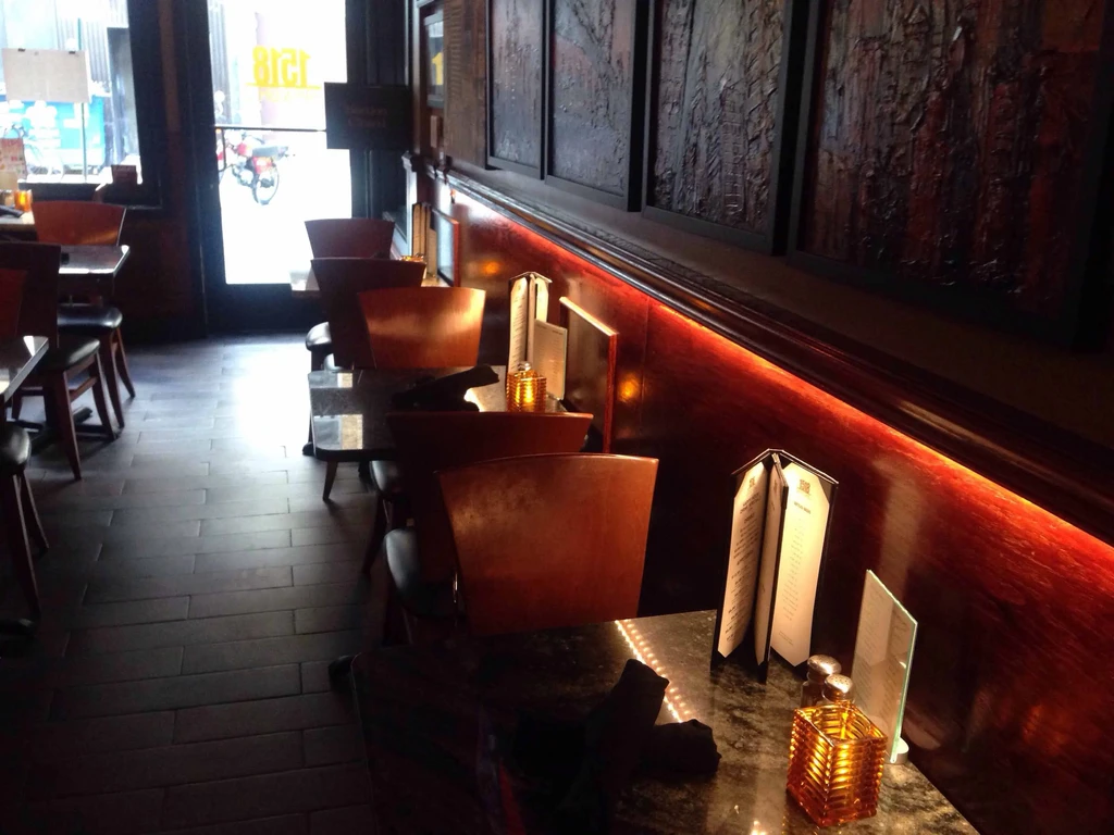 Dimly lit, cozy restaurant interior with red LED light and art.