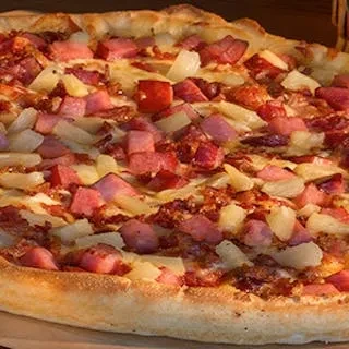 A whole Hawaiian pizza topped with ham, pineapple, bacon, and cheese.