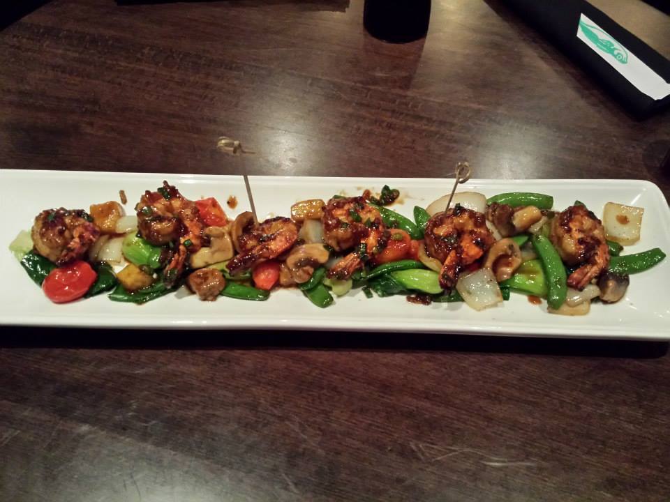 Glazed shrimp and stir-fried vegetables on a white plate.
