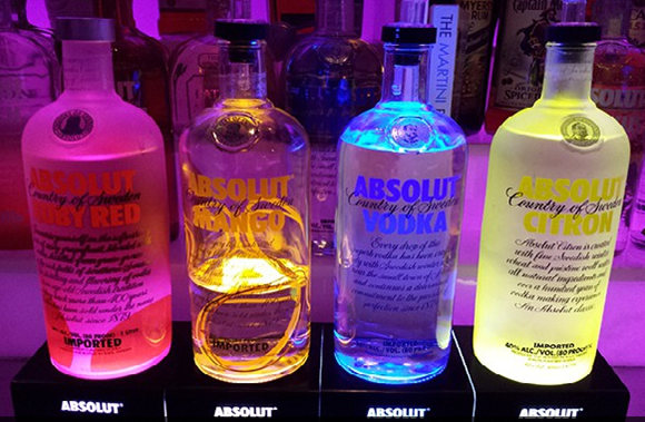Four glowing Absolut vodka bottles: Ruby Red, Mango, Vodka, Citron.