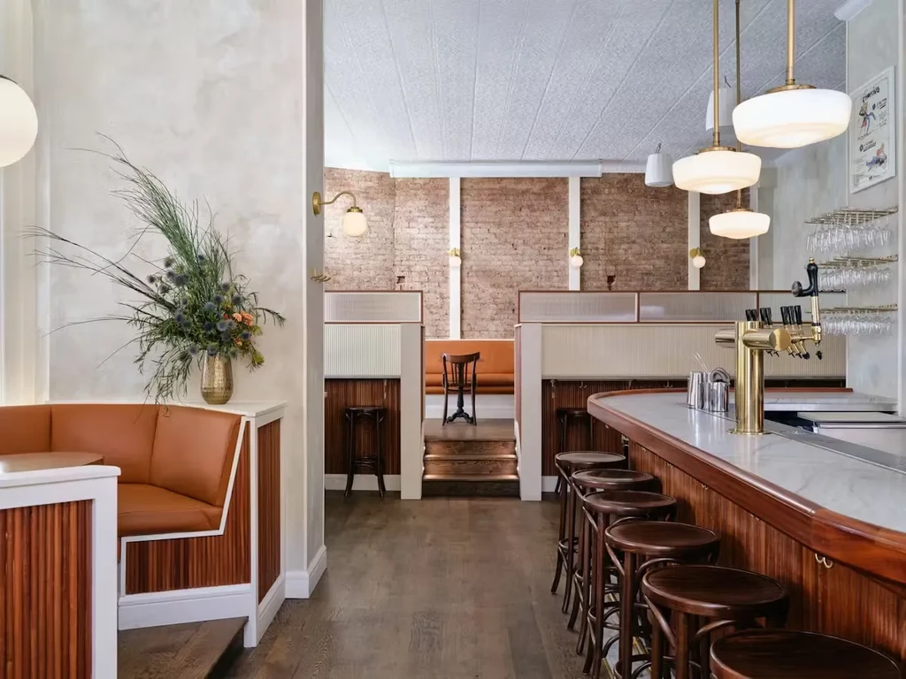 Restaurant bar with brown booths, wooden stools, and brick walls.