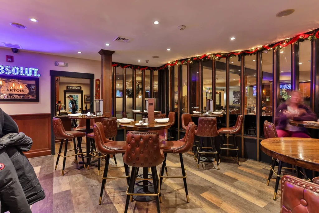 Modern restaurant interior with high-top tables, brown leather stools, and garland.