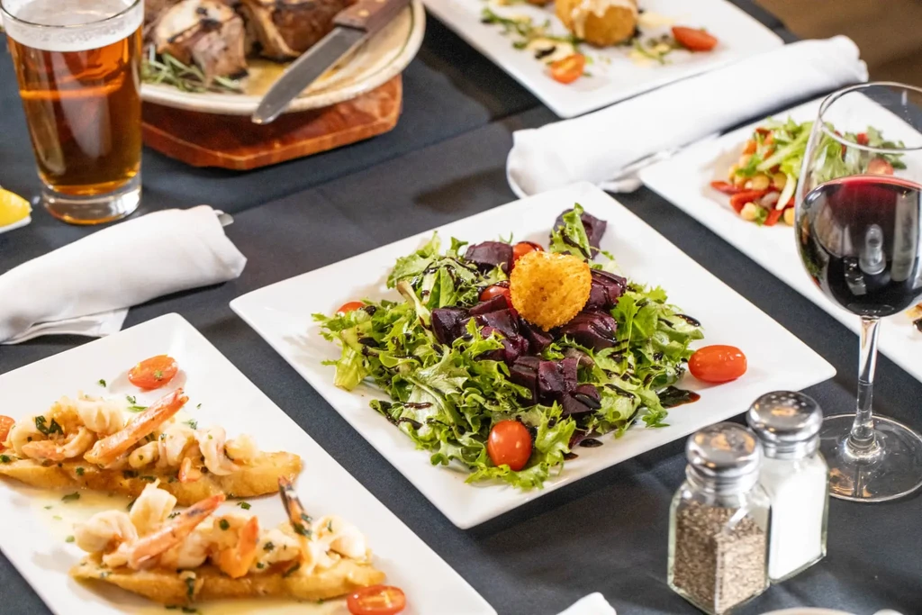 A dining table set with various gourmet food and beverages.