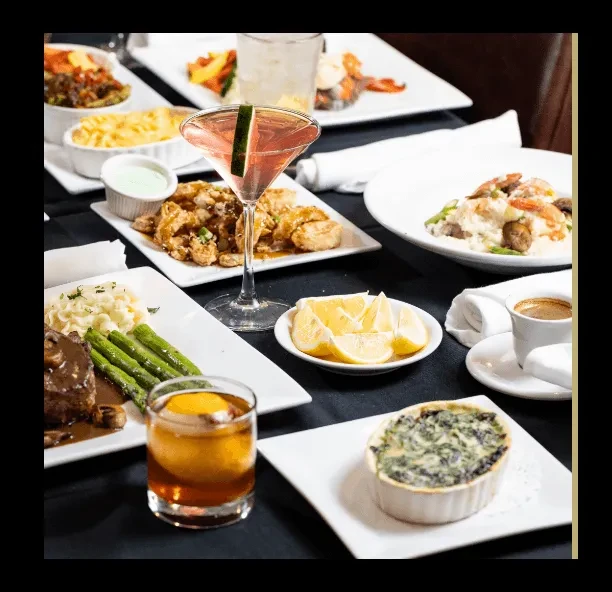 Vibrant restaurant table spread with steak, calamari, pasta, and cocktails.