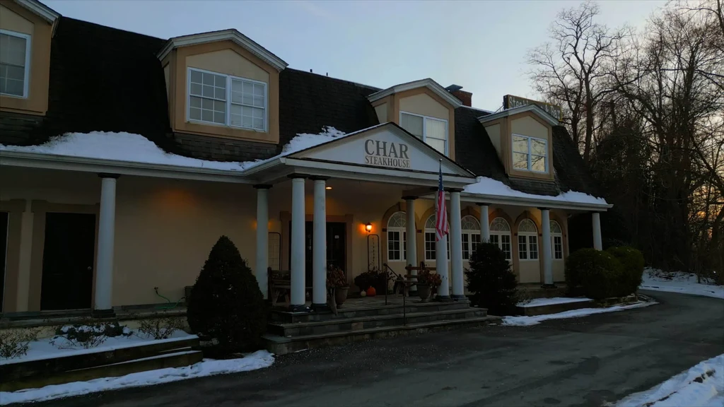CHAR STEAKHOUSE building exterior with classical columns, snow, and an American flag.