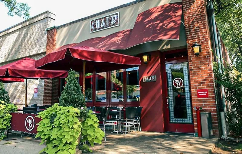 A storefront for "Chat 19" with outdoor seating under red umbrellas.