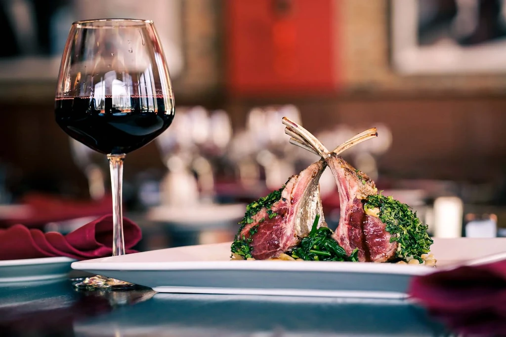 Rack of lamb and red wine glass on a restaurant table.
