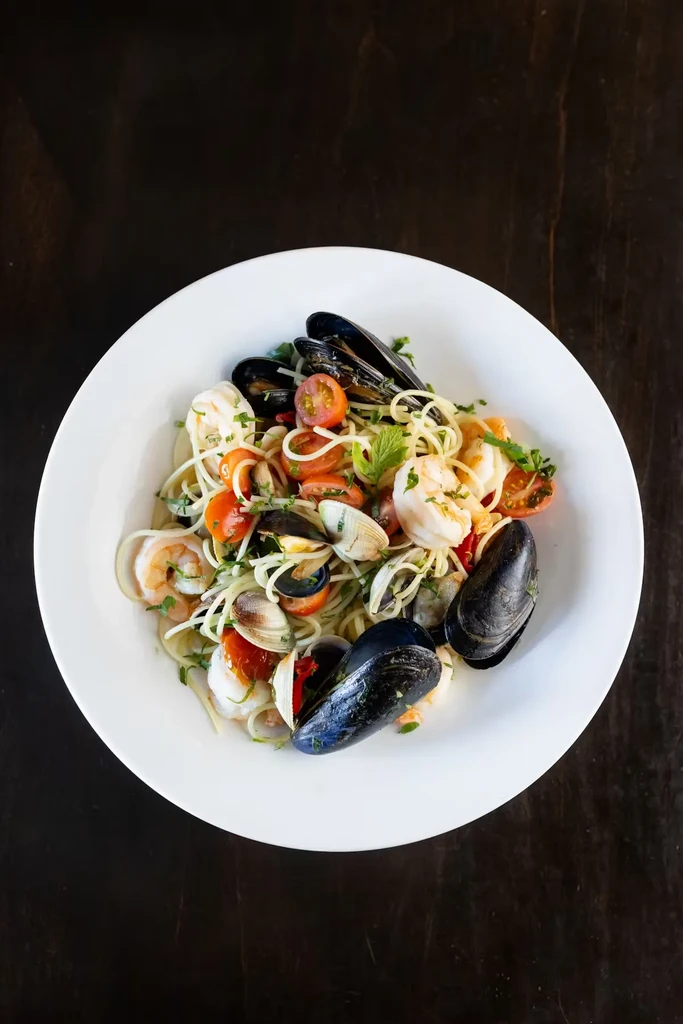Overhead view of seafood pasta with mussels, shrimp, clams, and cherry tomatoes.