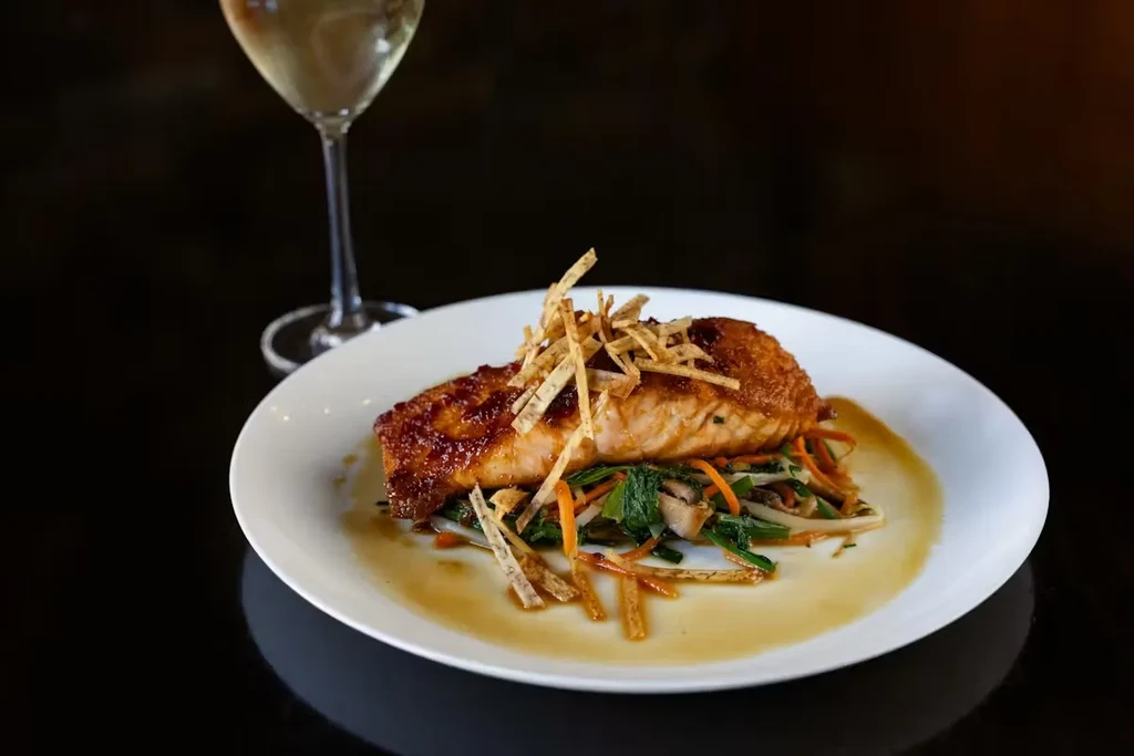 Salmon fillet with crisp topping and vegetables on a white plate.