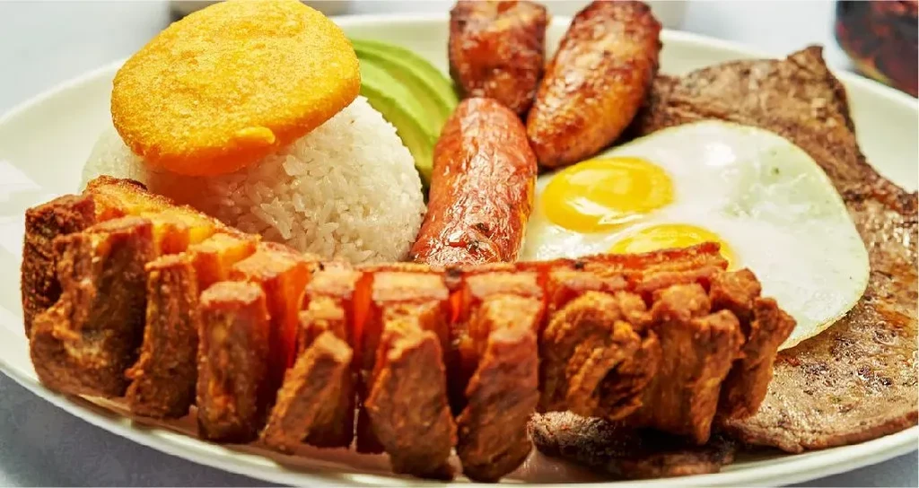 Bandeja paisa with meat, eggs, rice, avocado, sausage, and plantains.