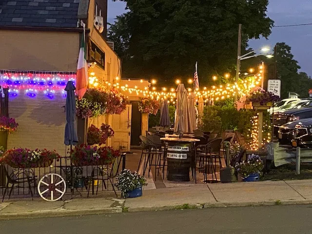 Exterior of a restaurant decorated with lights and plants at dusk.