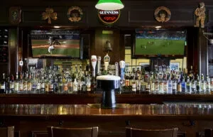 A well-stocked bar with two TVs showing sports and a Guinness tap.