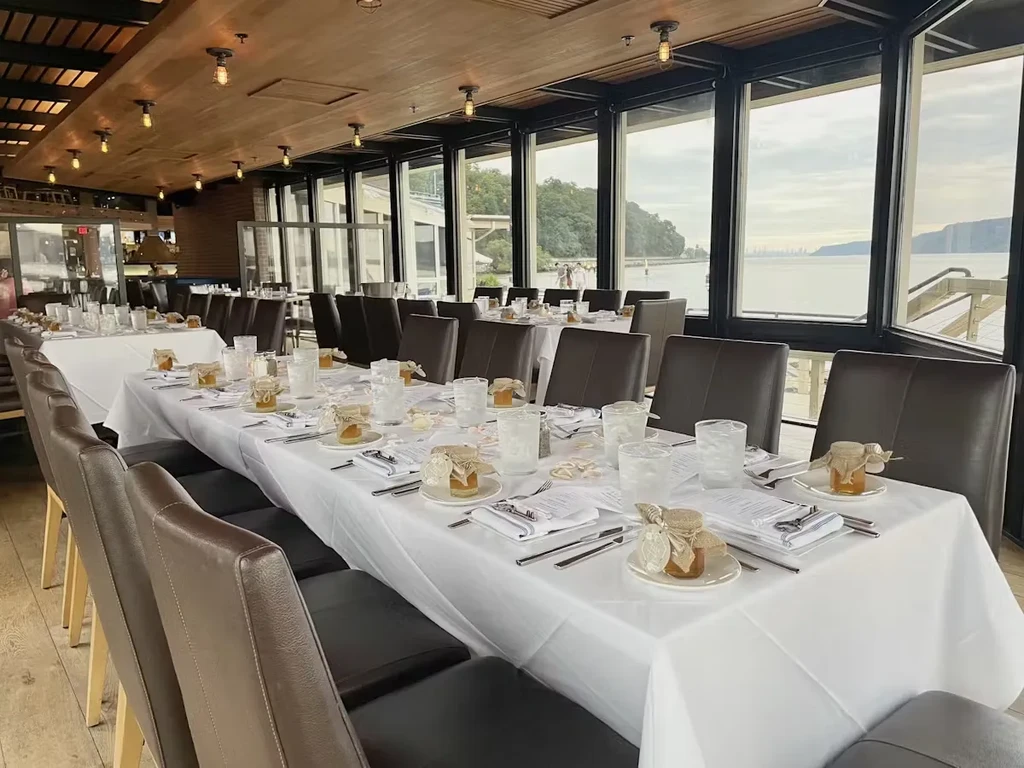 A long table set for an event in a waterside restaurant.
