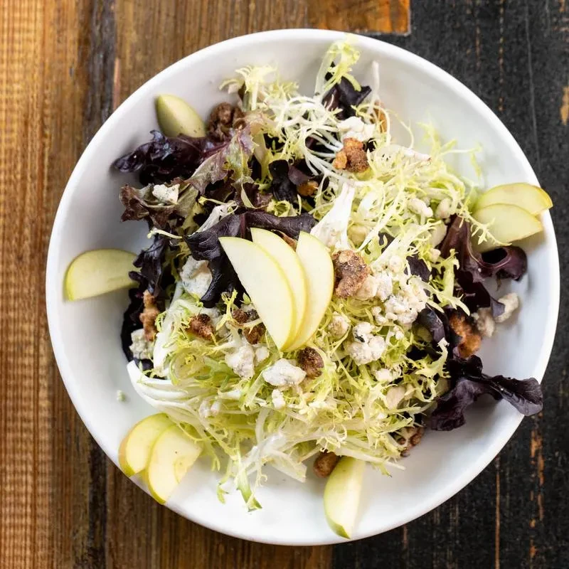 Overhead view of a salad with apples, blue cheese, and frisee.