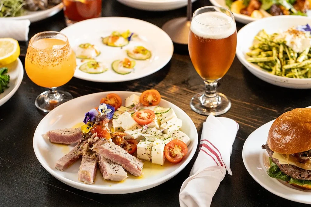 A dining table set with various plates of food and two drinks.