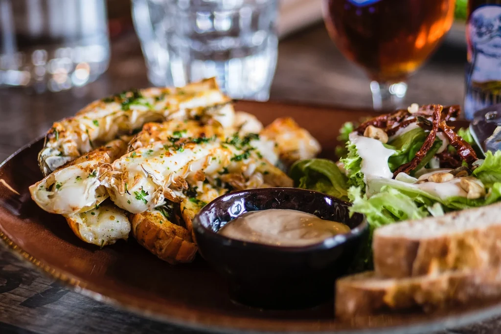 A platter of lobster, salad, dipping sauce, and bread.