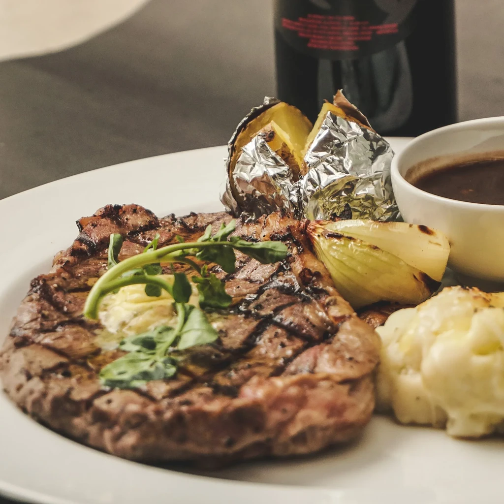 Grilled steak with baked potato, mashed potatoes, onion, and gravy.
