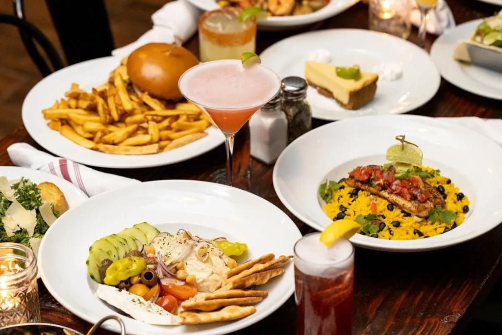A table laden with multiple plates of food, drinks, and desserts.