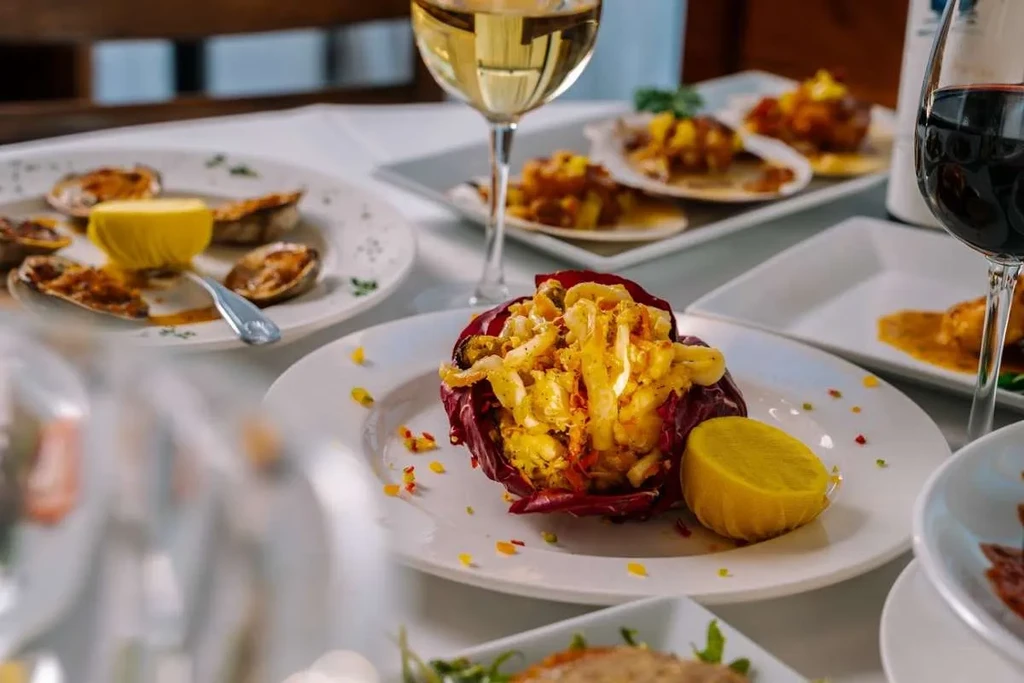 A table set with various seafood dishes and wine glasses.