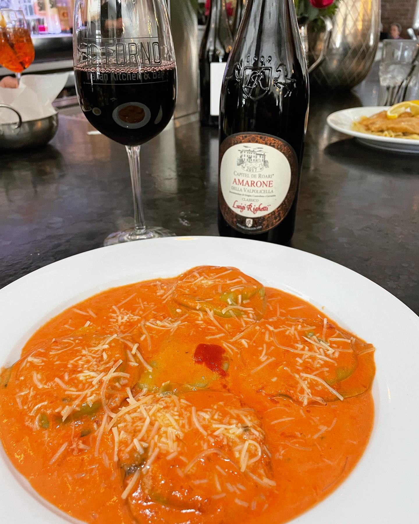 Ravioli with orange sauce, cheese, red wine and Amarone bottle.