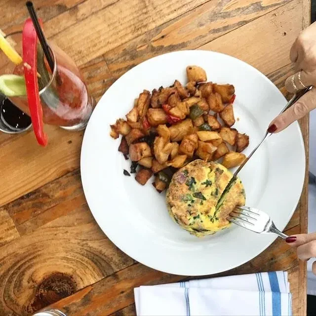 Overhead shot of person cutting an omelet next to home fries.