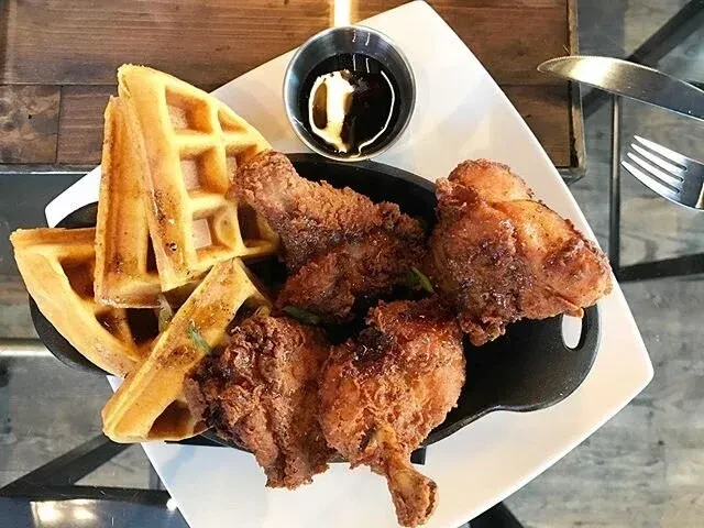 Fried chicken and waffles with syrup on a white plate.