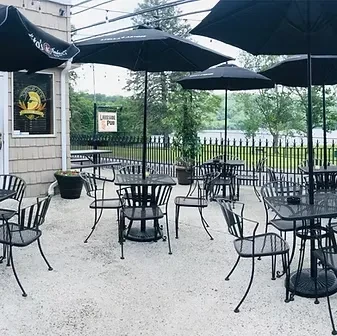 Outdoor patio of Lakeside Pub with tables, umbrellas, and lake view.