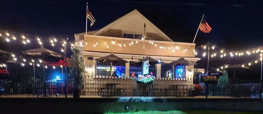 Restaurant exterior at night, lit by string lights over its patio.