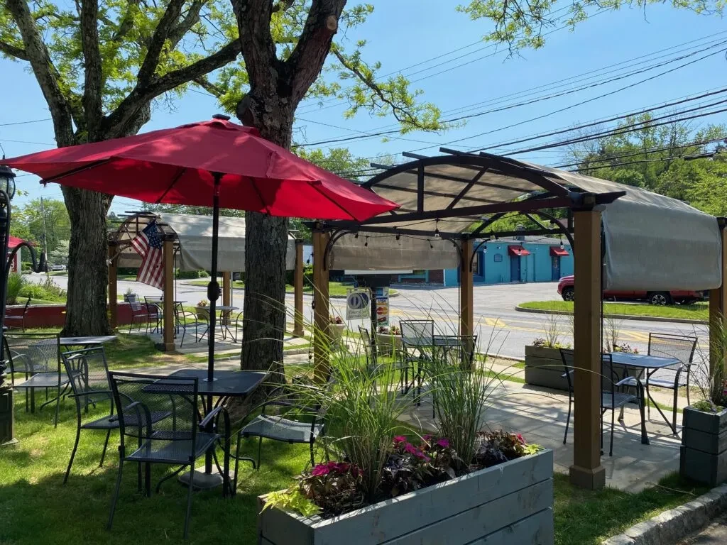Outdoor patio seating area with a red umbrella and pergola.