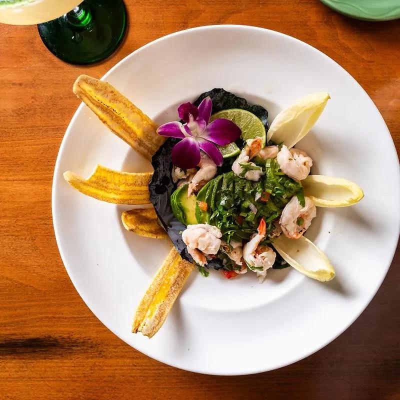 Shrimp ceviche with avocado, plantains, and a purple orchid garnish.