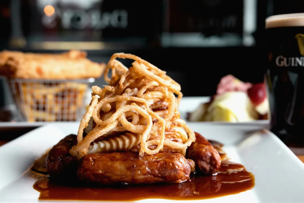 Sausage and mash with gravy, onion rings, fries, and a Guinness.