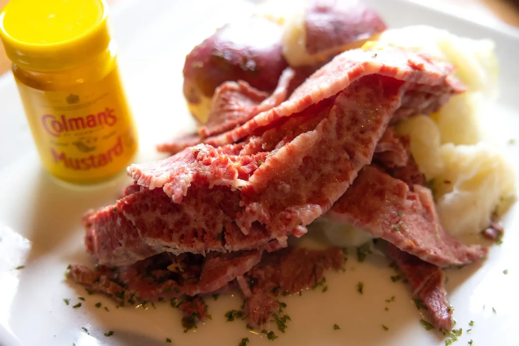 Corned beef meal, potatoes, cabbage, and Colman's Mustard on a plate.