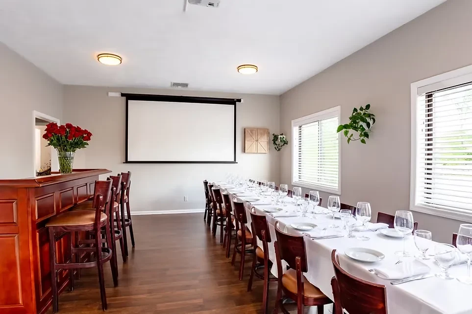 Elegant private dining room with bar, projection screen, and set table.