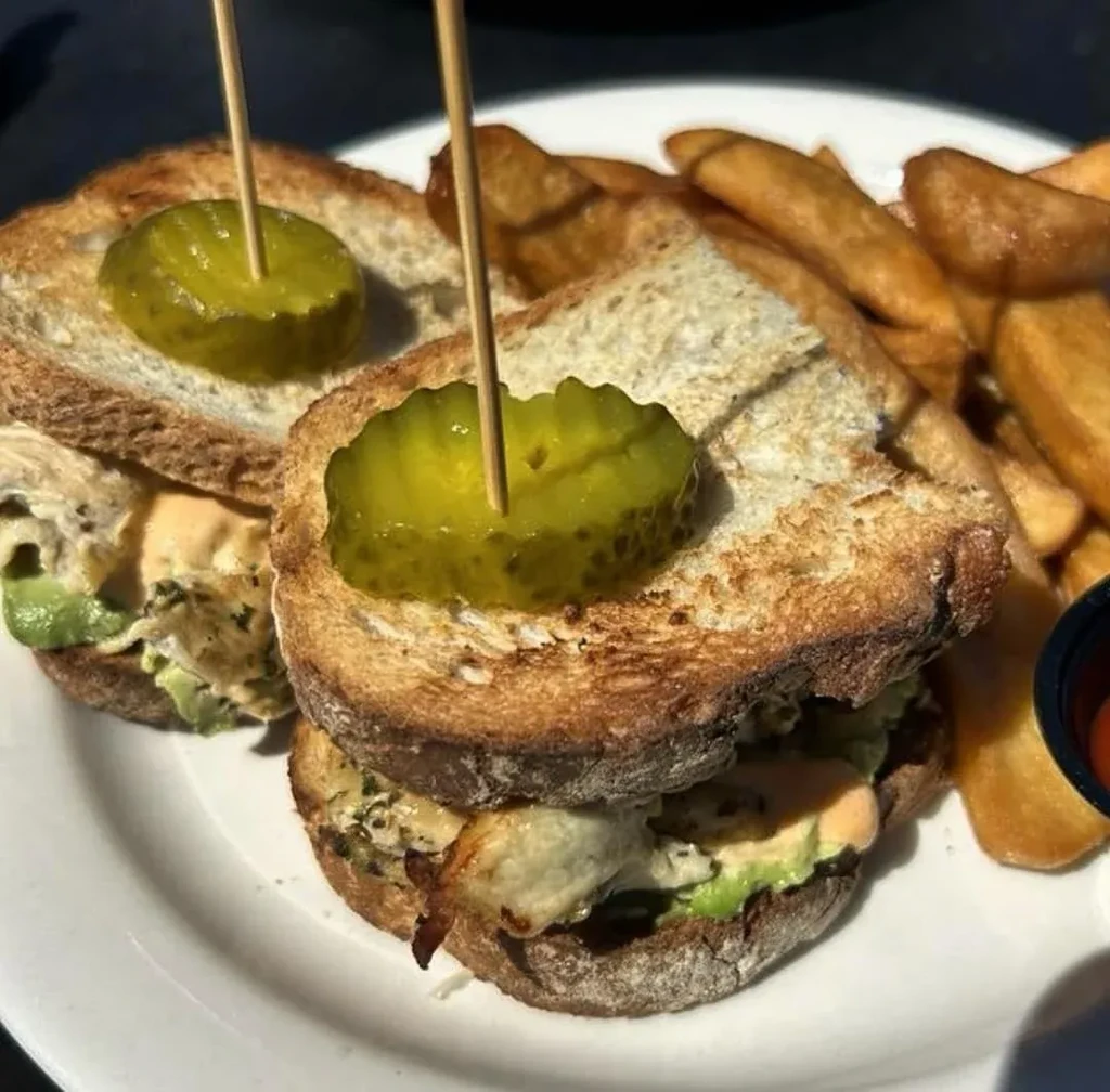 Two mini sandwiches with pickles and a side of french fries.