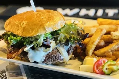 A burger with fries, salad, and sliced tomatoes and cucumber on a plate.