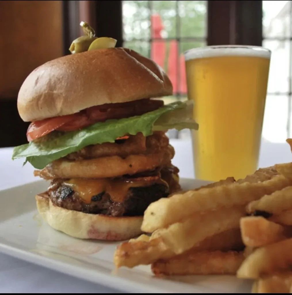 Burger with onion rings, fries, and a beer.
