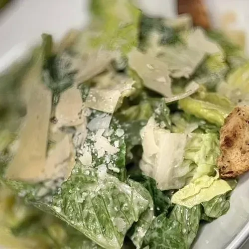 Close-up of a Caesar salad with lettuce, cheese, and croutons.