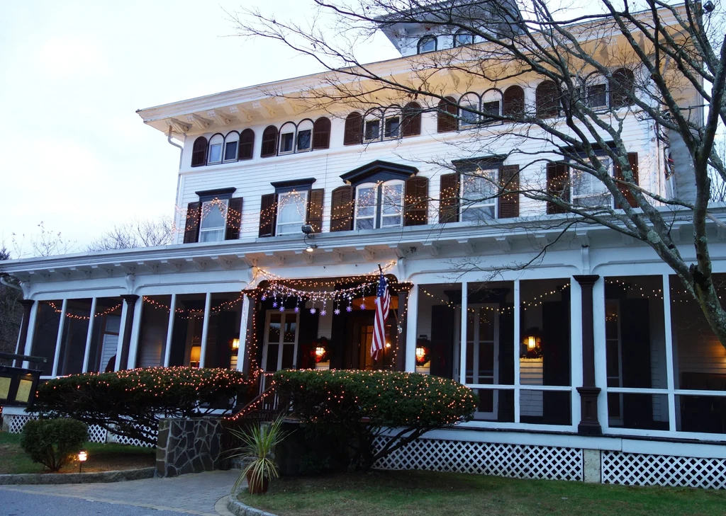Historic white building festively lit with string lights and American flag.