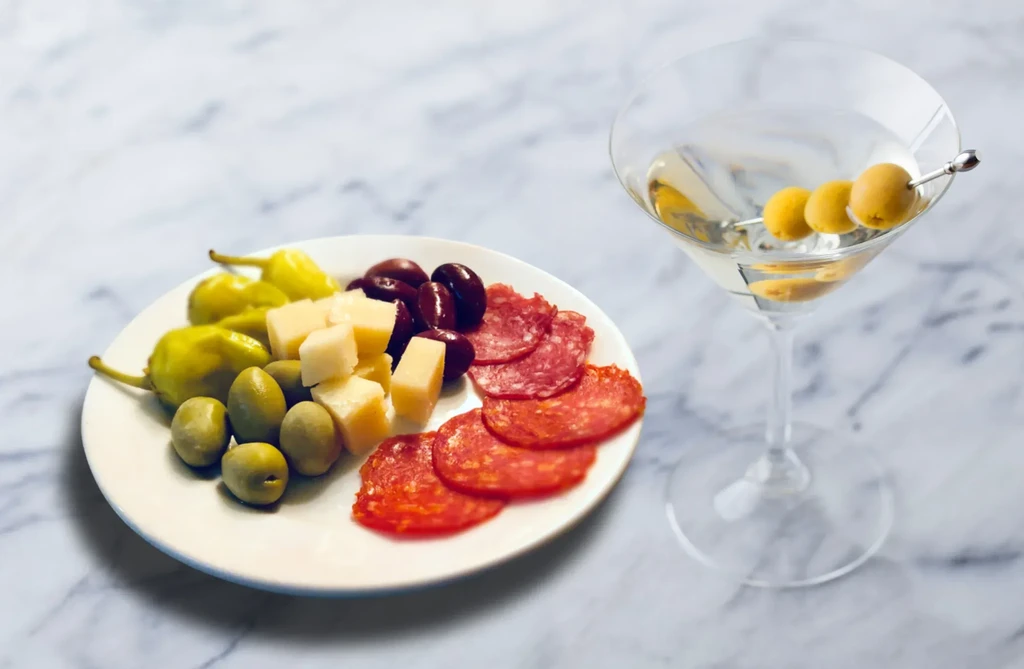 Still life: Appetizers, martini with olives, on a marble surface.
