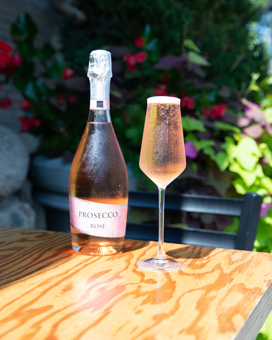 Prosecco Rosé bottle and sparkling wine in a glass on a wooden table.