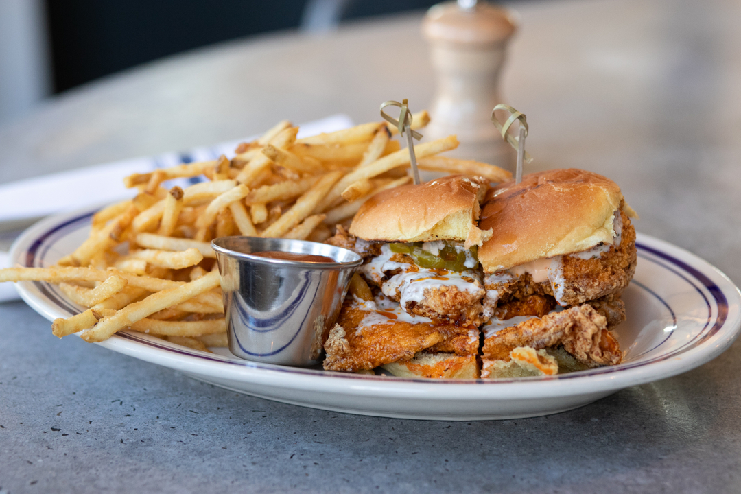 Fried chicken sliders with fries and dipping sauce on a plate.