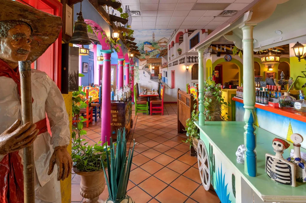 Vibrant Mexican restaurant interior with statue, mural, and Tequila Bar.