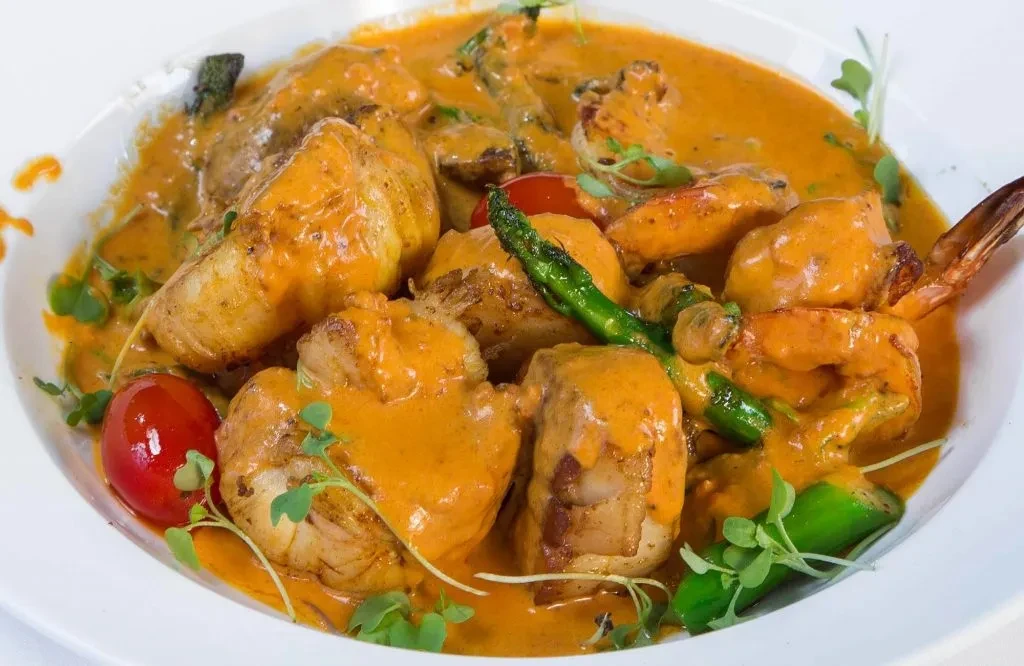 Seafood stew with red sauce, scallops, shrimp, tomatoes, and asparagus.