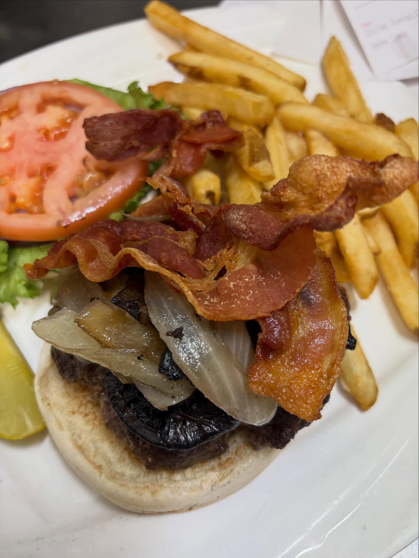 Open-faced burger with bacon, grilled onions, lettuce, tomato, and fries.