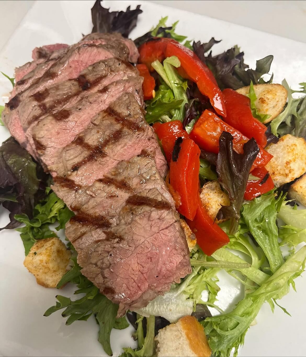 Grilled steak, roasted red peppers, and croutons on mixed greens.