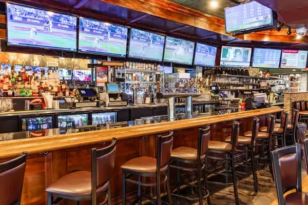 A sports bar with many televisions showing games above a long bar.