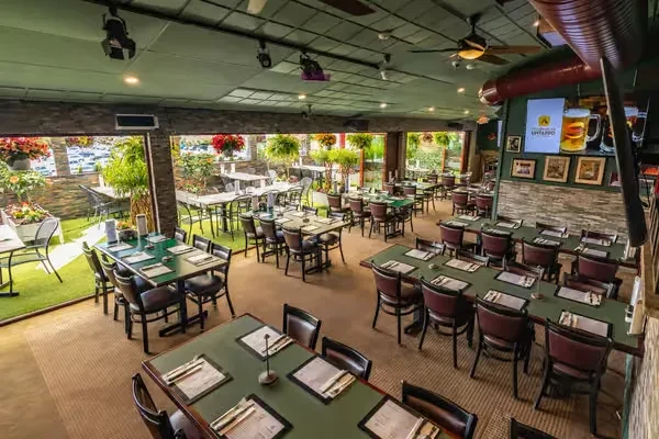 An empty restaurant with green tables and an outdoor patio.