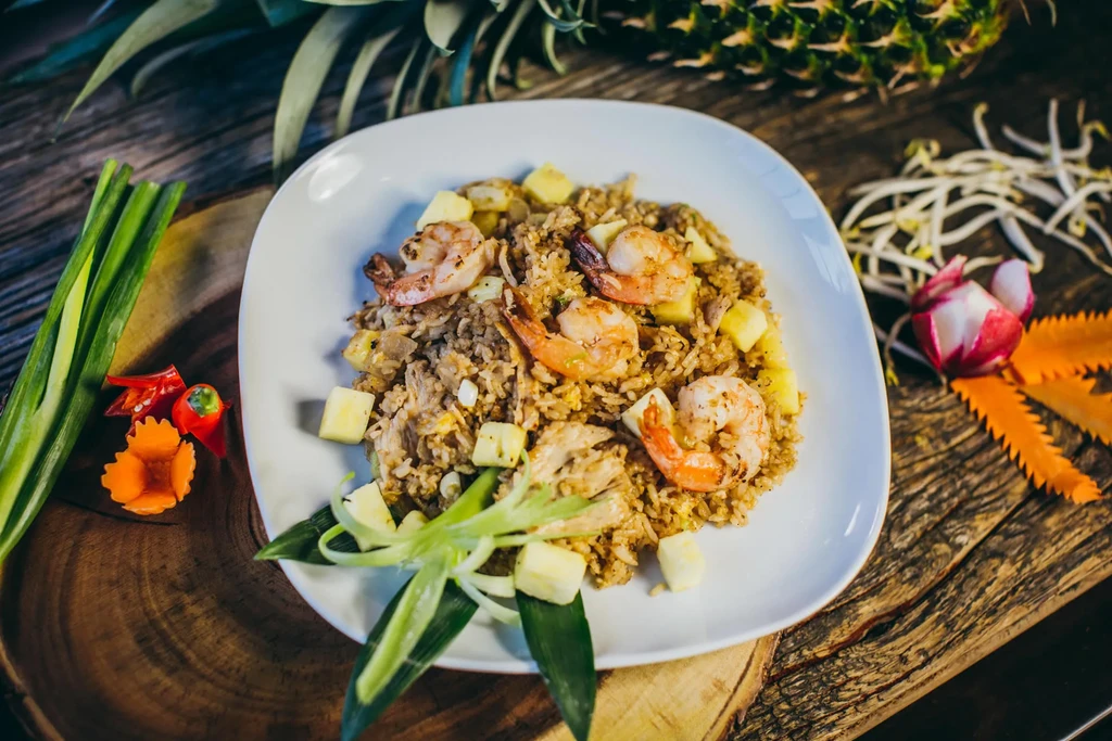 Pineapple fried rice with shrimp, garnished with fresh vegetables.