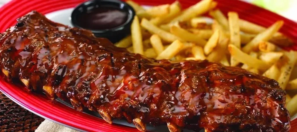 Barbecue ribs with sauce, french fries, and a side of sauce.