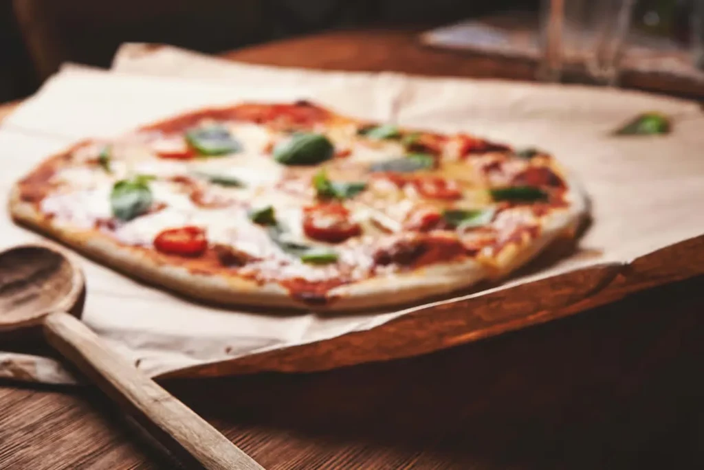 A blurry image of a margherita pizza on a wooden surface.